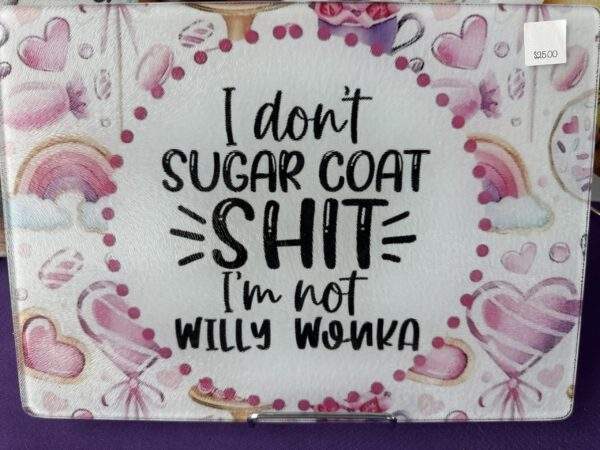 A cutting board with images of candy and hearts, surrounding fun text that reads, "I don't sugarcoat shit, I'm not Willy Wonka"