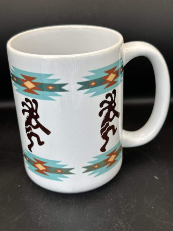 A white mug featuring blue, yellow, and red southwest patterns and black dancing kokopelli figures.