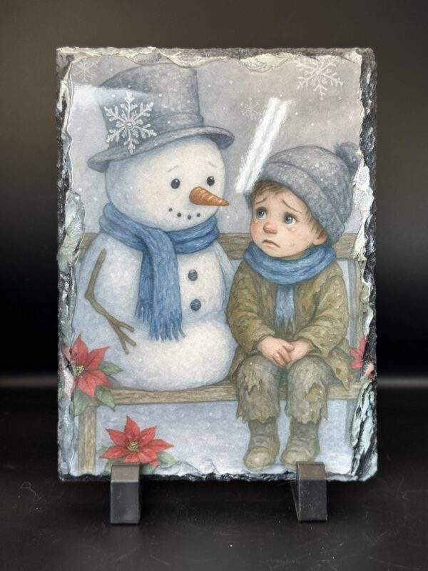 A rectangular stone slate showing a cozy scene of a downcast child seated besides a friendly snowman on a bench on a winter's day.
