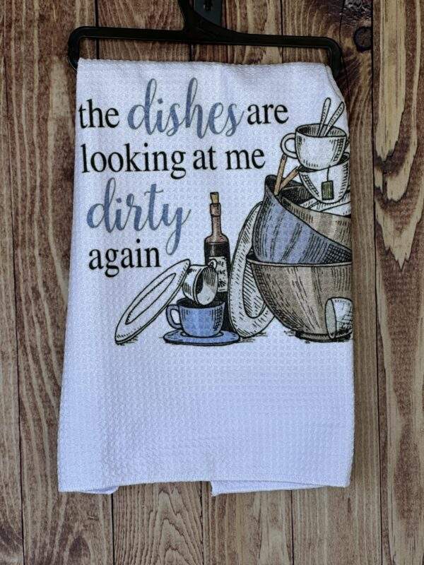 white, waffle weave kitchen dish towel with images of a stack of dishes. Text reads "the dishes are looking at me dirty again"