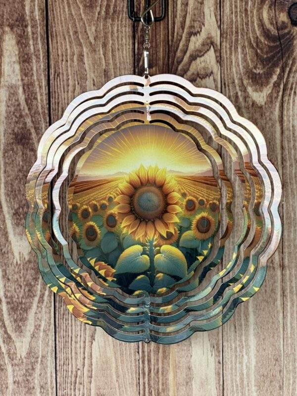 Wind spinner with bright sunrise towards the back, larger sunflower in center and smaller sunflowers around it.