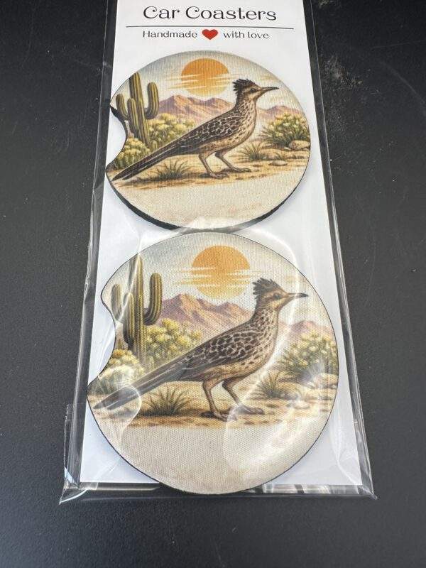 A set of 2 car coasters. Design: a roadrunner waits in the desert before a yellow sun and a saguaro cactus.