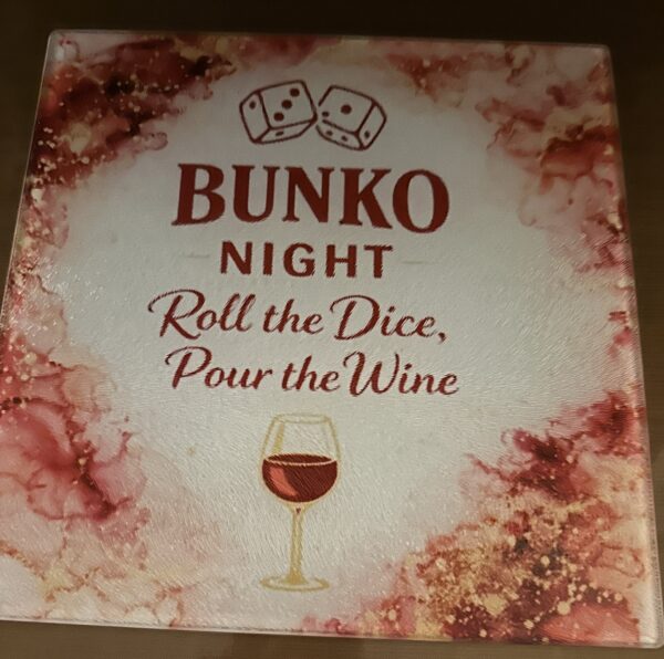A glass cutting board with wine-colored ink surrounding a wine glass and dice, and the words, 'Bunko Night, roll the dice, pour the wine'