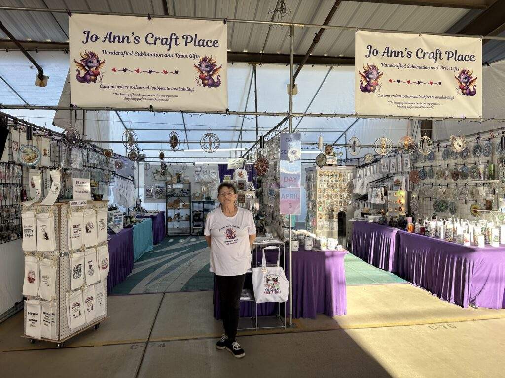 Jo Ann standing in front of her Mesa Marketplace location, a ton of crafts on display behind her.