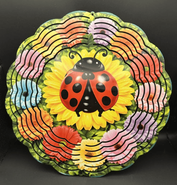 A colorful garden bed of bright flowers and a huge ladybug resting in the center atop a yellow flower bloom.